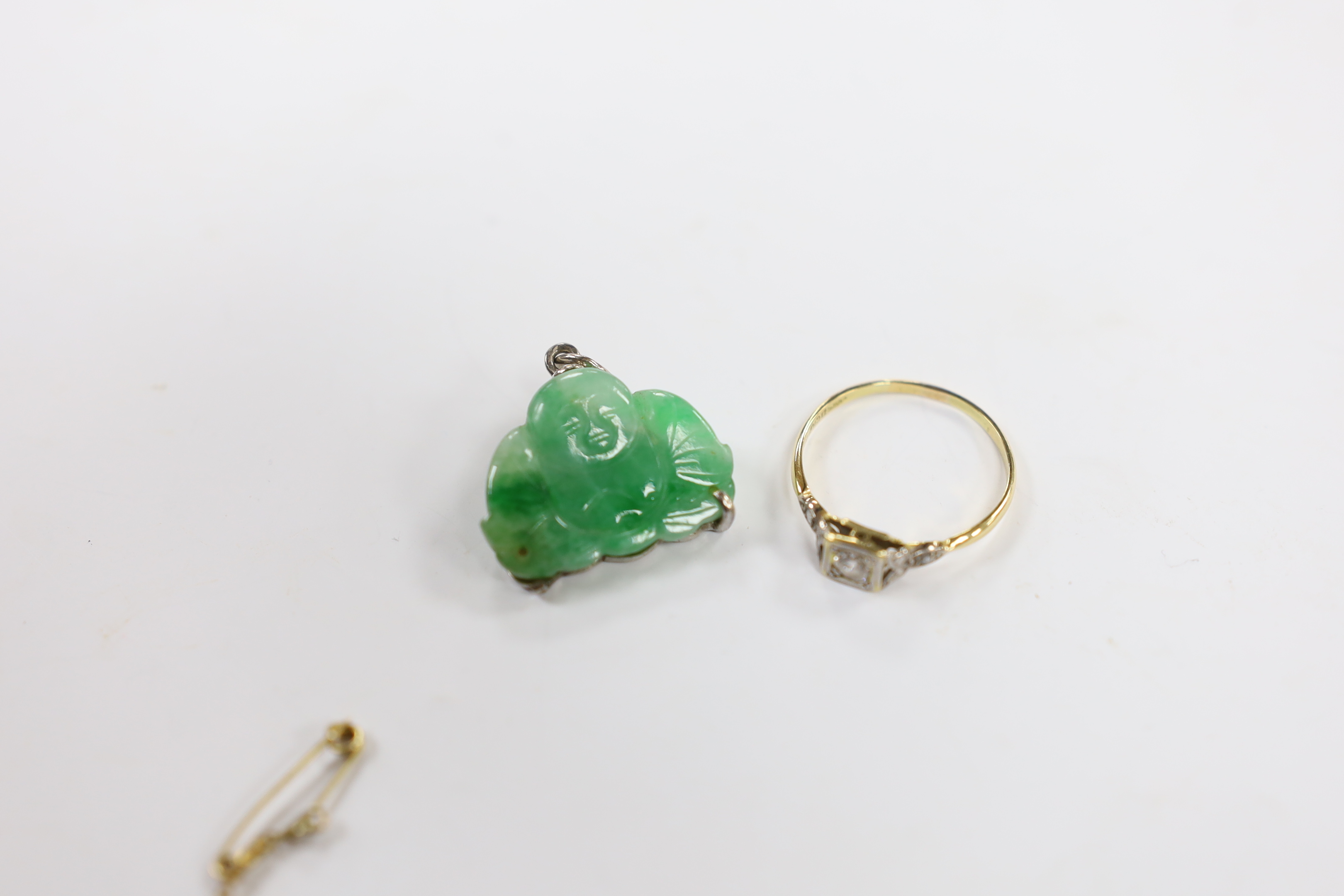 An Edwardian 9ct, aquamarine and seed pearl cluster set bar brooch, 54mm, a Chinese mounted jade Buddha pendant and an 18ct and single stone diamond set ring, with diamond chip set shoulders.